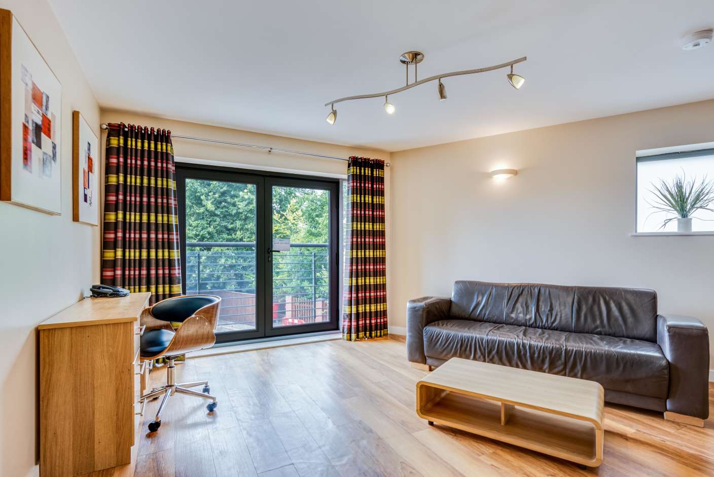 Spacious apartment living area with faux leather sofa and Juliet balcony